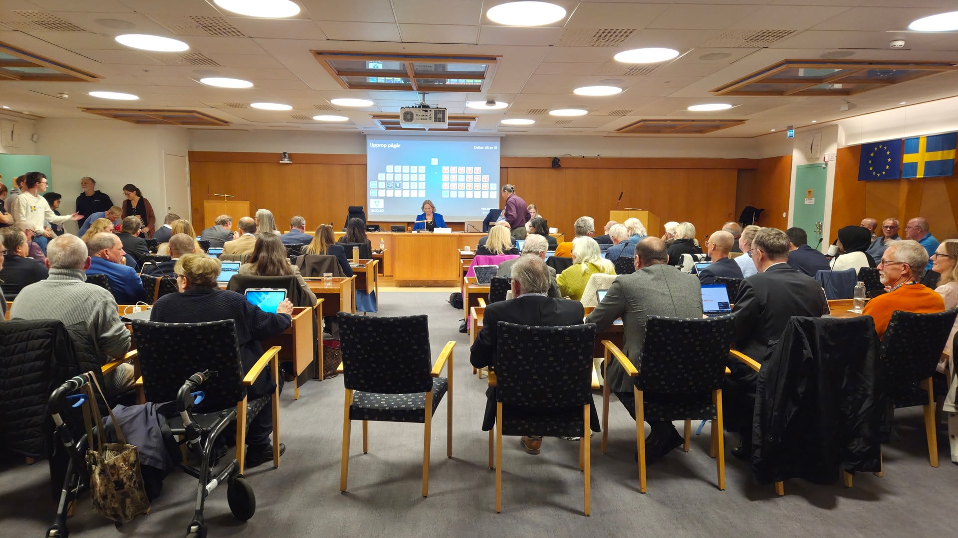 En grupp människor som sitter på stolar framför en projektorskärm.