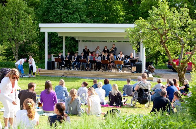 Bild på herrgårdsscenen med besökare och band. 