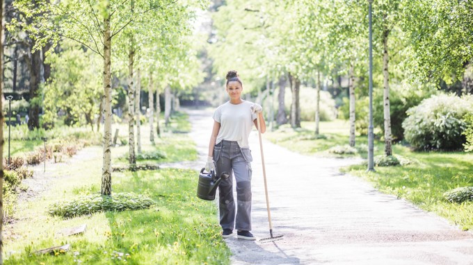Sommarjobbare med en kratta och vattenkanna.