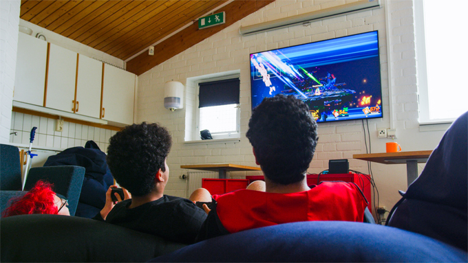 Bild tagen bakifrån på ungdomar som spelar tv-spel. 