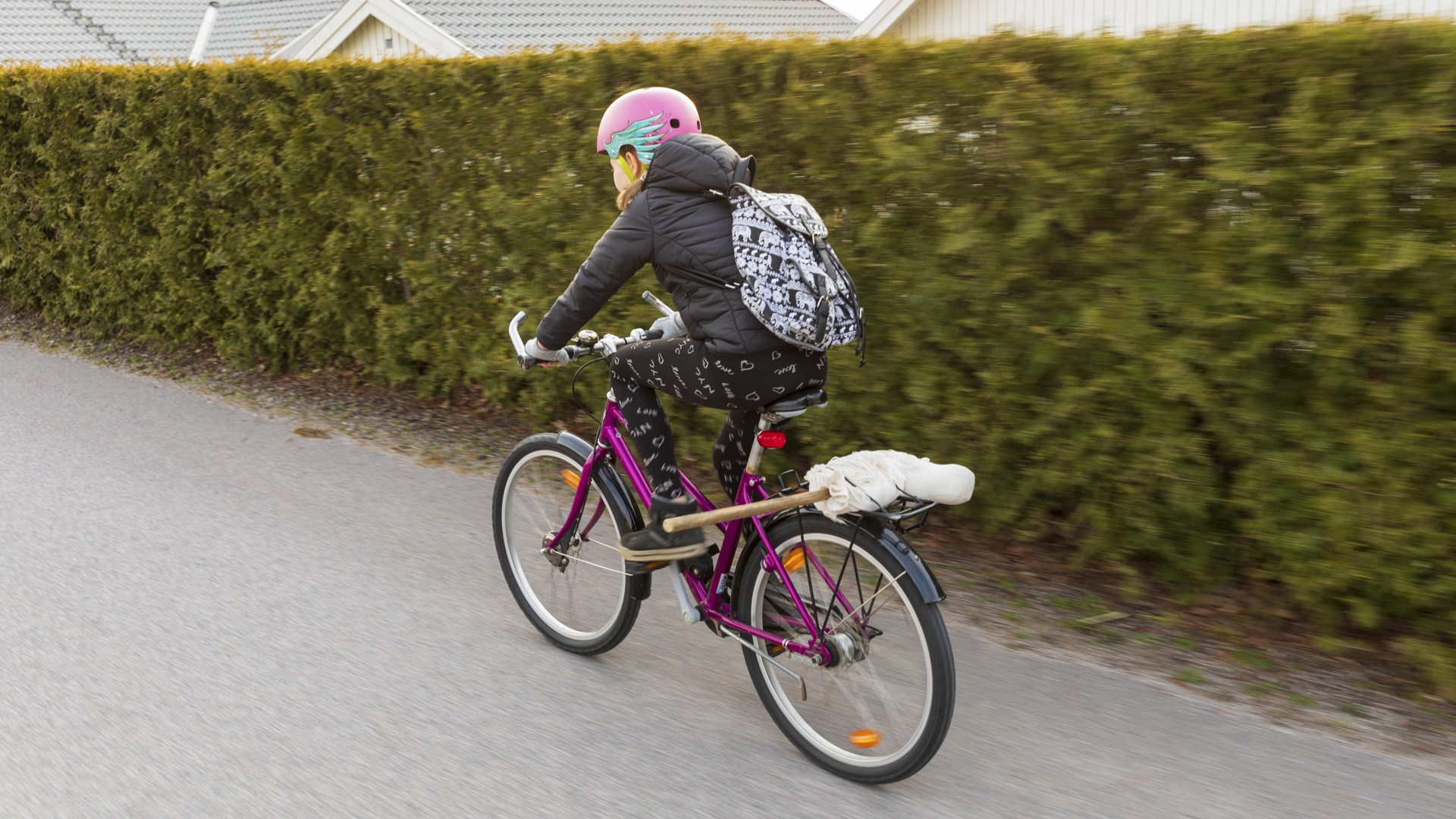 Bilden visar en flicka som cyklar på en lila cykel.