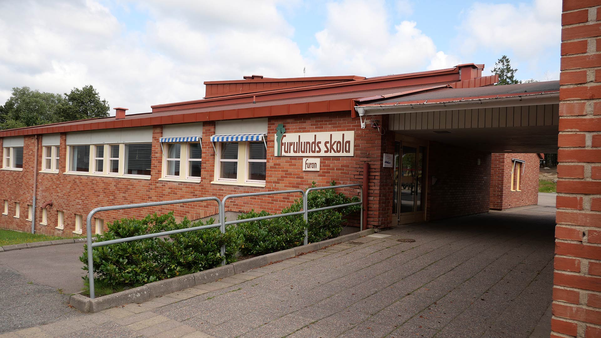 Bilden visar Furulunds grundskola. Det är en tegelbyggnad med en skylt på fasaden. 