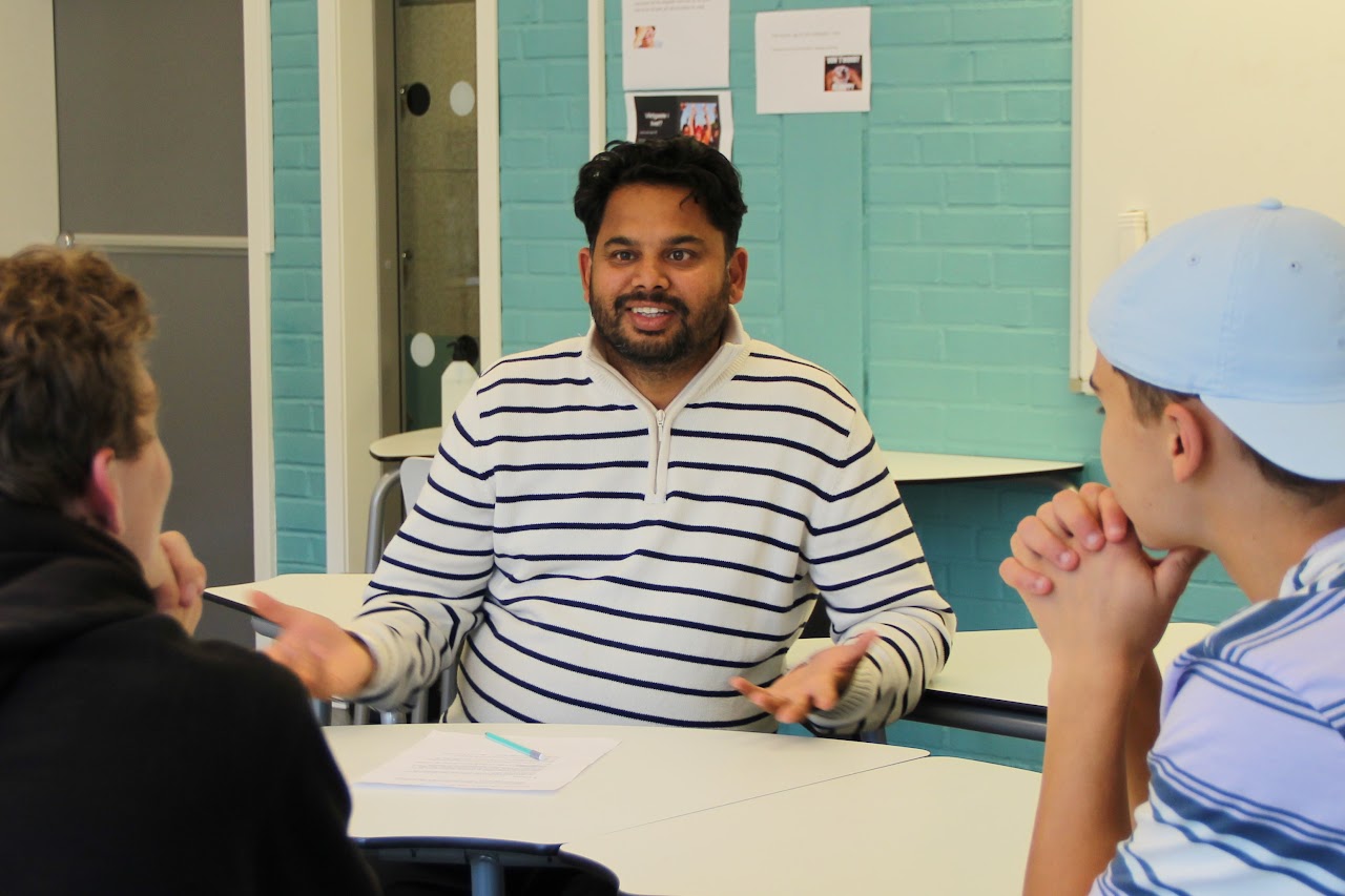 Bilden visar tre elever från dem olika klasserna som sitter och diskuterar kring ett bor. 