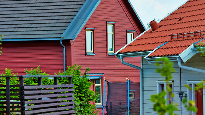 Bild på ett rödmålat hus med grått tak och ett vitmålat hus med ljusbrunt tegeltak.
