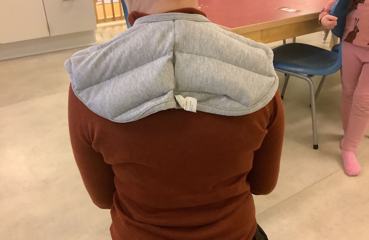 Bilden visar en person som sitter med ryggen vänd mot kameran och har en axeltyngd på sig. 