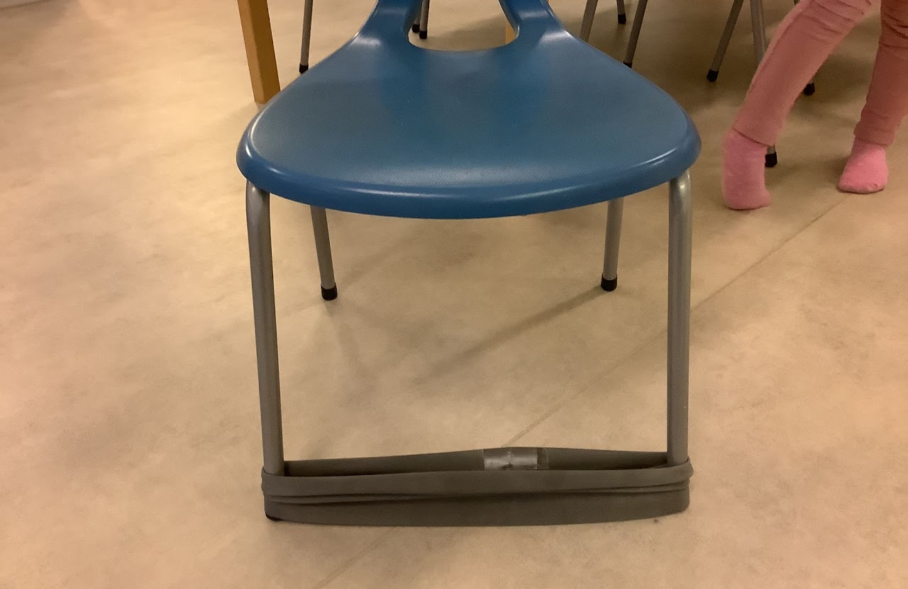 Bilden visar en så kallad sparkstol, en blå stol med elastiska band mellan frambenen. 