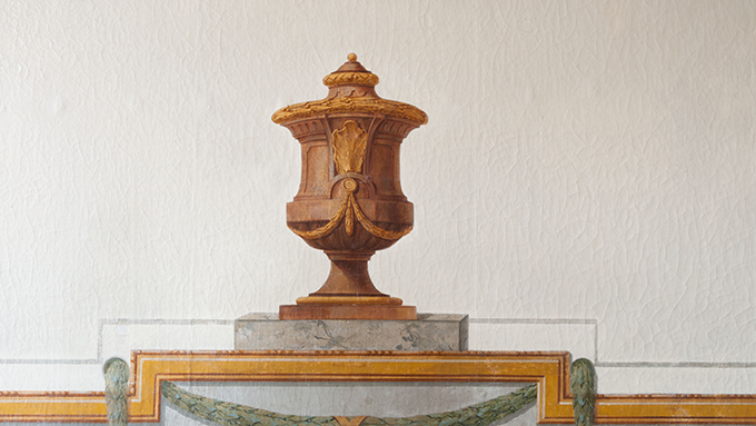 Bild på detalj från en 1700-talstaper. Detaljen föreställer en brun urna.
