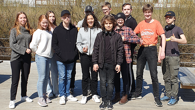 Bilden  visar en gruppbild med tolv unga personer som fotograferats utomhus.