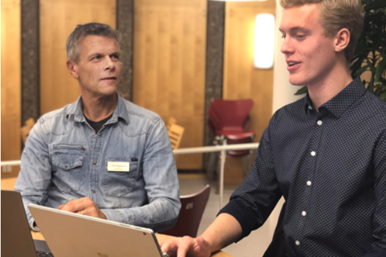 Bilden visar Joakim Magnusson och Nils Grimbeck som sitter bredvid varandra vid ett bord, på bordet står två stycken bärbara datorer med skärmarna uppfällda. 