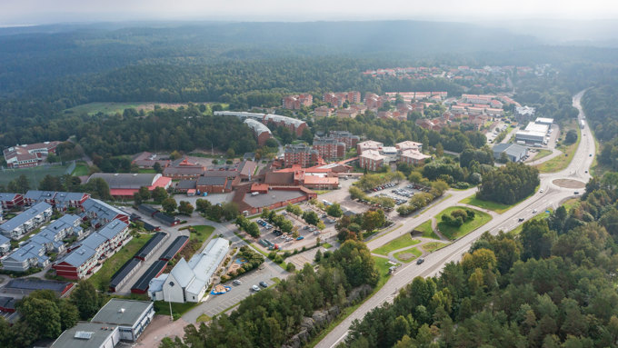 Drönarbild över Landvettervägen och Furulund centrum med vägen, bebyggelsen och omgivande grönområden sedda ovanifrån.