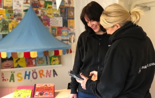 Bilden visar två lärare som står och tittar på en läsplatta tillsammans.