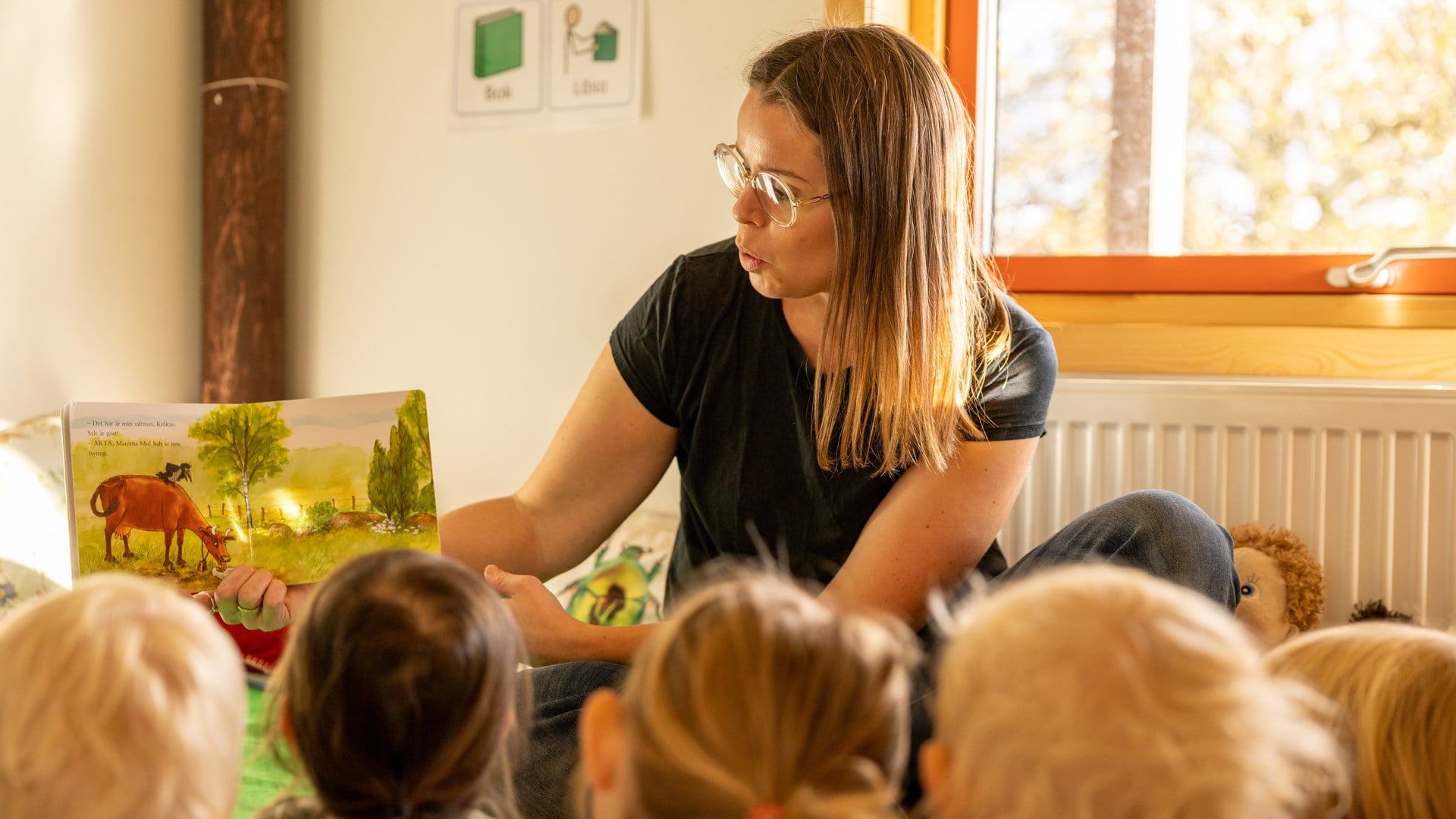 Förskolepedagog läser för barn.