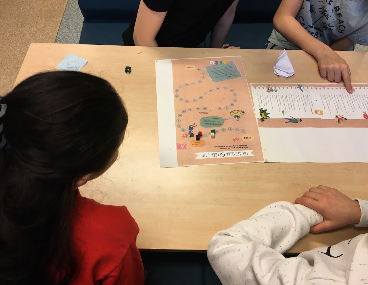 Bilden visar fyra stycken elever som sitter vid ett bord och spelar The Speaking Skills game. 