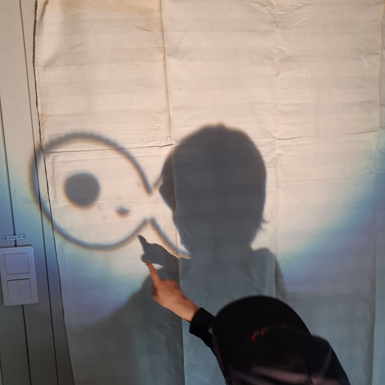 Bilden visar ett barn som har ett ljussken bakom sig så att hens skugga bildas på en vägg. 