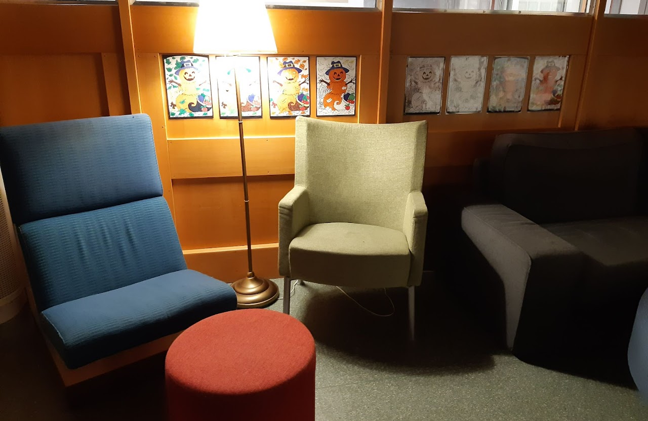 Bilden visar två fåtöljer med en golvlampa emellan och fotpallar.  