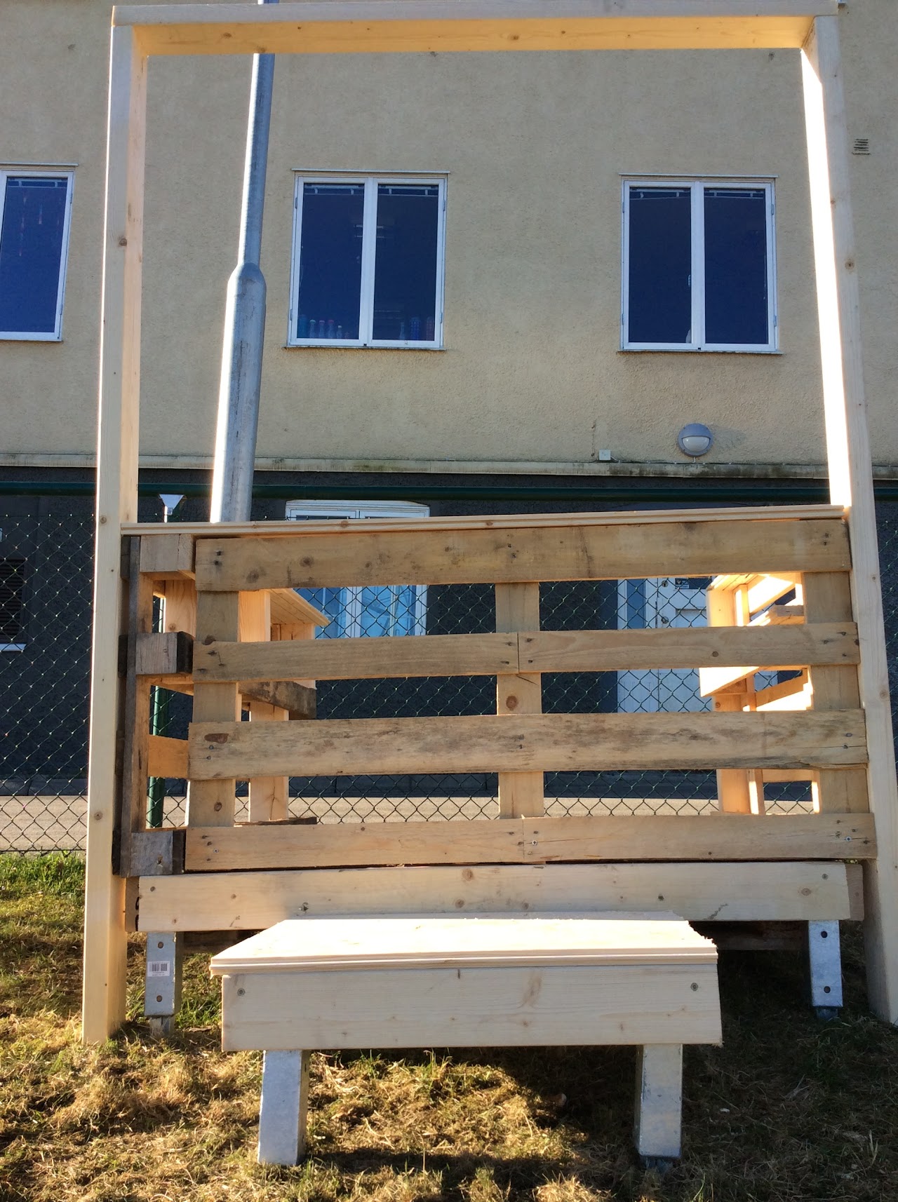 Bilden visar en kiosk byggd av EU pallar, framför kiosken står en pall byggd i trä. 