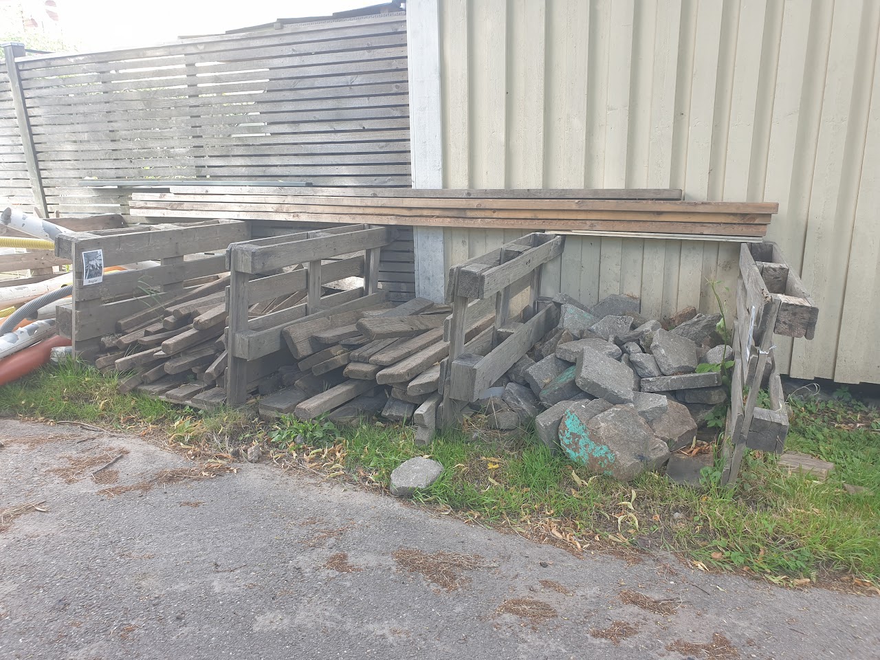 Bilden visar EU pallar ställda på kant, emellan dem ligger stora stenar, spill bitar samt längre bitar av trä. 