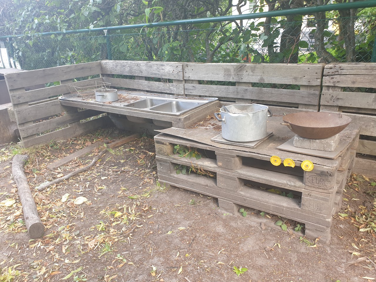 Bilden visar ett ute kök byggt av EU pallar och en rostfri diskbänk. 