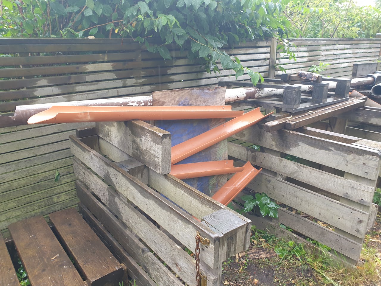 Bilden visar EU pallar uppställda på högkant, mellan dem ligger flera hängrännor kors o tvärs. 