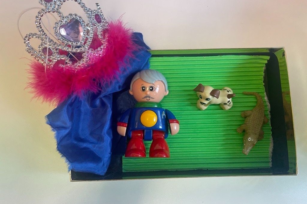 Bild på leksaksfigurer  i en låda med grön botten.