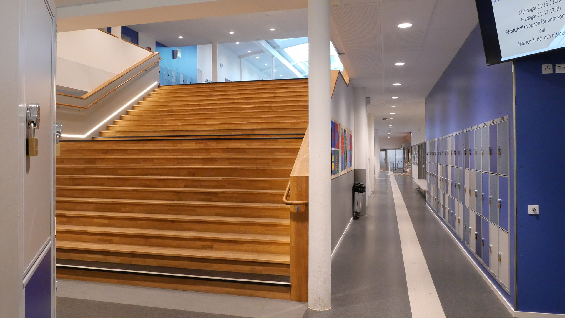 Mitt i bilden syns en stor trappa som leder upp till andra våning på Stadsparkskolan. Till höger på bilden syns flera rader med elevskåp. 