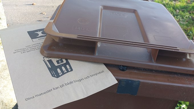 Bild på ett avfallskärl med en matavfallspåse klämd under locket på kälet.