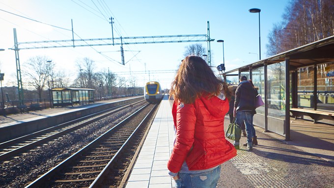 Bild på ung person som väntar på anländande tåg på perrongen vid Partille station.