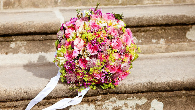 Bild på brudbukett, bunden av rosa, lila och limegröna blommor.
