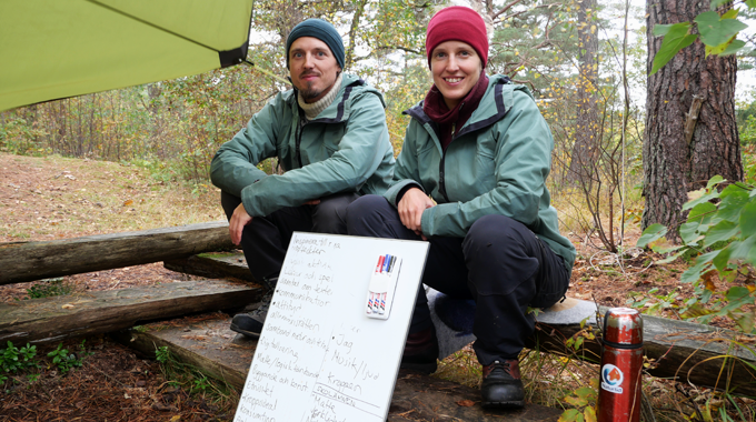 Bild som visar Tobias Sloth Hansen och Hanna Isa Olausson som sitter på en stock i skogen. 