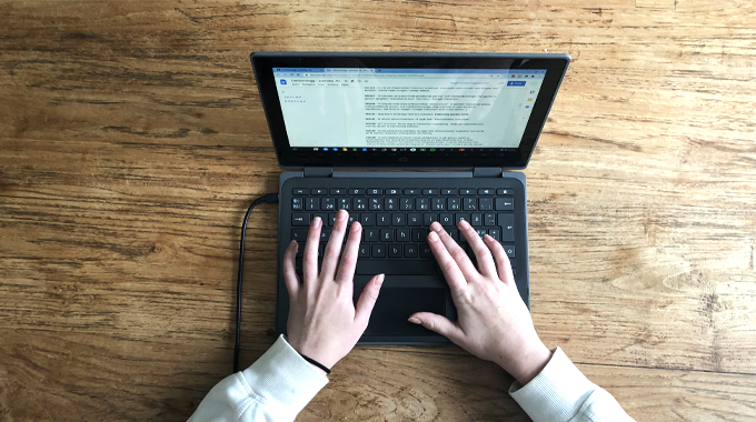 Bild som visar två händer som skriver på en dator. 