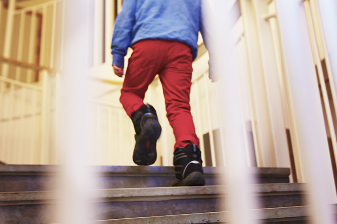 Ung pojke går uppför en trappa i trapphus.