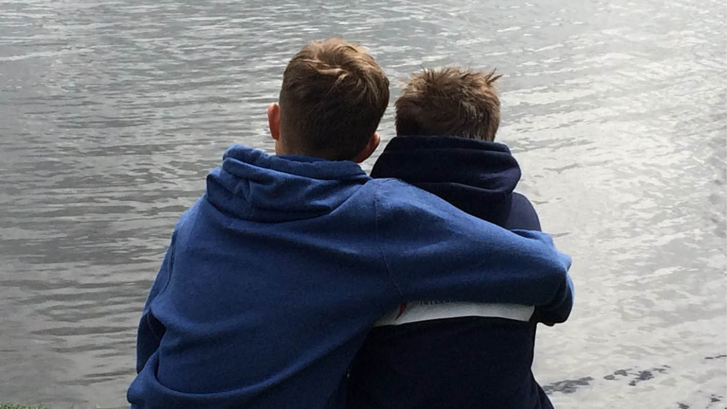 På bilden syns två bröder, varav den äldre brodern har lagt sin arm om den yngres axlar.