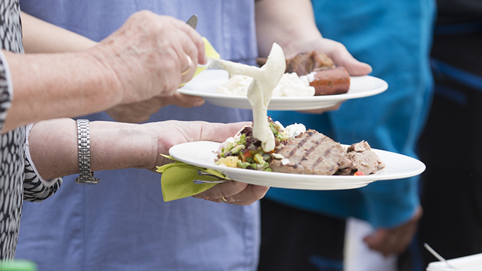 Bild på äldre person som lägger upp lunchmat på en tallrik.