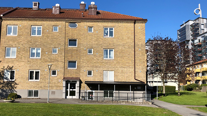 Bild på ett trevånings hyreshus i gult tegel.