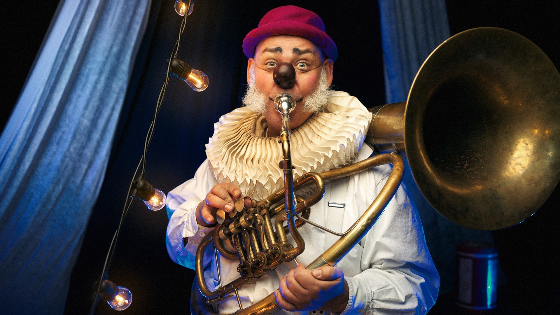 Bild på en clown tittandes in i kameras samtidigt som han spelar på en trombon