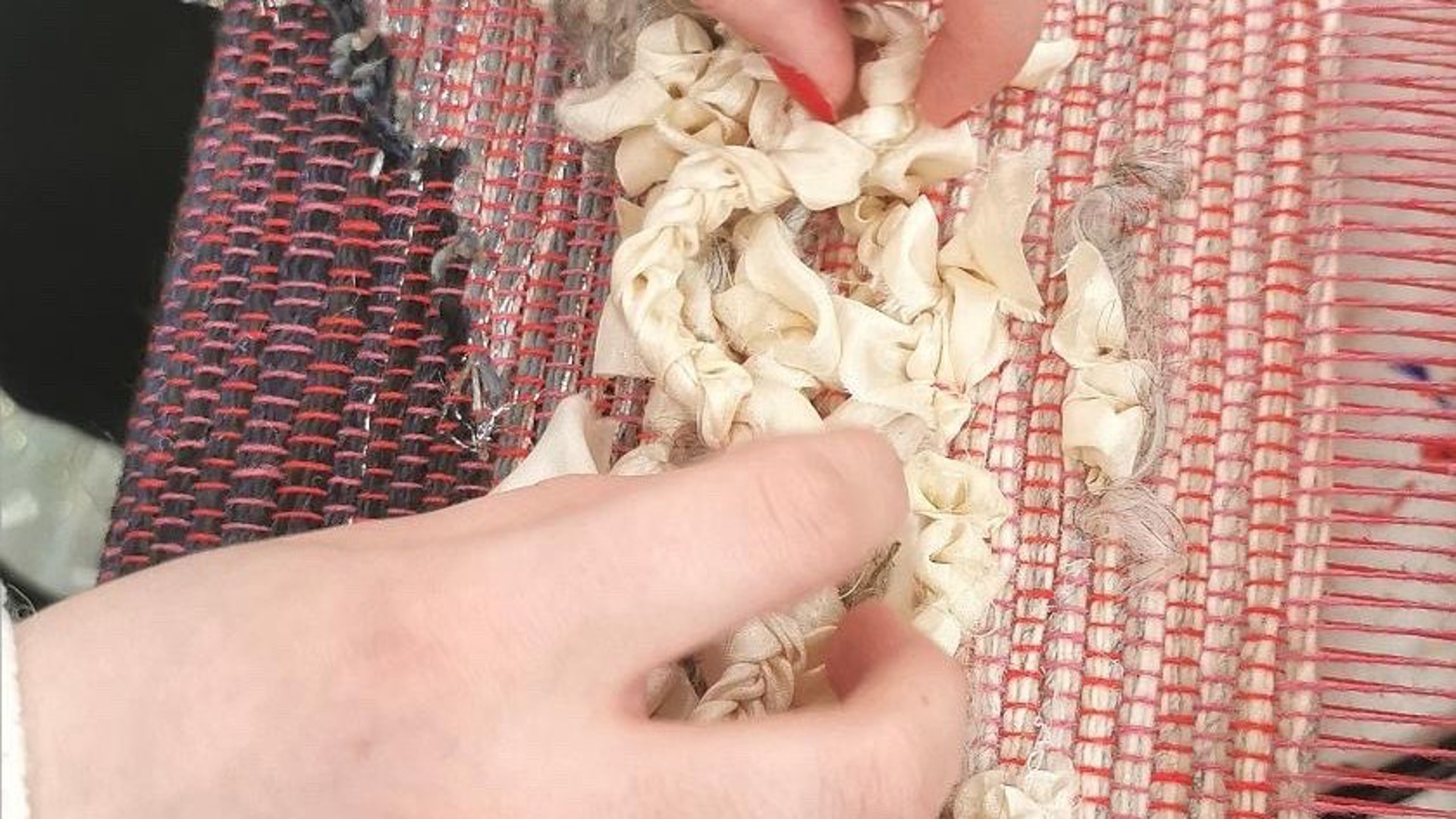 Bild på vävd textil och händer.