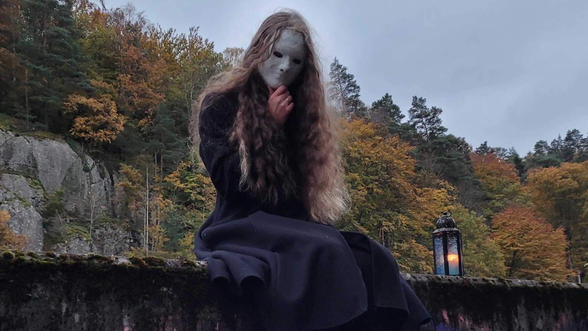 Bild på flicka med ansiktsmask som sitter i höstnatur