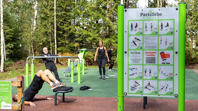 Bild på utegymmet i Öjersjö. Ett par personer tränar i de olika redskapen.